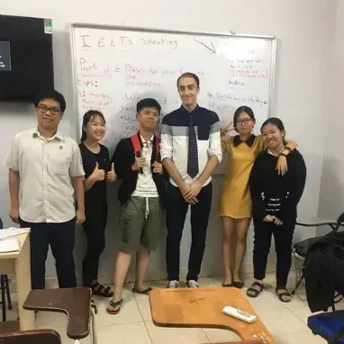 James with his IELTS speaking class in front of a whiteboard